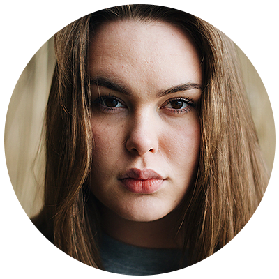 Young woman with brown hair looking at the camera. Portrait photography headshot.