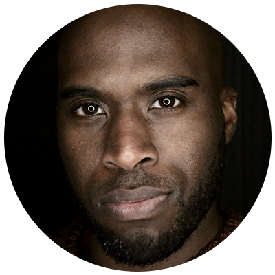 Close-up portrait of a bald Black man with a beard, looking directly at the camera. Focus on self-care and mental well-being.