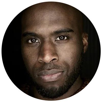Close-up portrait of a bald Black man with a beard, looking directly at the camera. Focus on self-care and mental well-being.